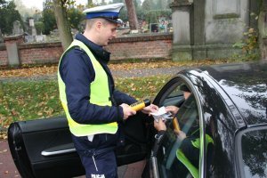 Policjant z Wydziału Ruchu Drogowego dokonuje kontroli trzeźwości kierowcy samochodu osobowego