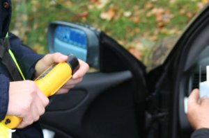 Policjant podaje kierowcy urządzenie do badania poziomu alkoholu w wydychanym powietrzu