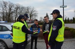 Policjanci z Komisariatu Policji w Sompolnie, Wydziału Prewencji, Wydziału Ruchu Drogowego oraz kapelan konińskich policjantów wręczają elementy odblaskowe