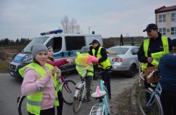 Policjanci z Komisariatu Policji w Sompolnie, Wydziału Prewencji, Wydziału Ruchu Drogowego oraz kapelan konińskich policjantów wręczają oświetlenie rowerowe i elementy odblaskowe
