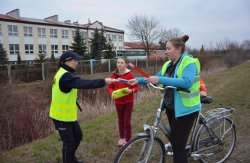 Policjantka z Wydziału Prewencji konińskiej komendy wręcza dzieciom na rowerach elementy odblaskowe i oświetlenie rowerowe