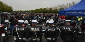 Funkcjonariuszee wydziału ruchu drogowego podczas zabezpieczenia zlotu motocyklowego w Licheniu. W tle widać uczestników zlotu oraz motocykle.