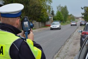 policjant mierzący prędkość samochodów przy pomocy laserowego miernika prędkości