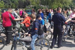 Dzielnicowy i burmistrz rozdają odblaski uczestnikom rajdu rowerowego