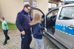 dzielnicowy prezentuje radiowóz policyjny