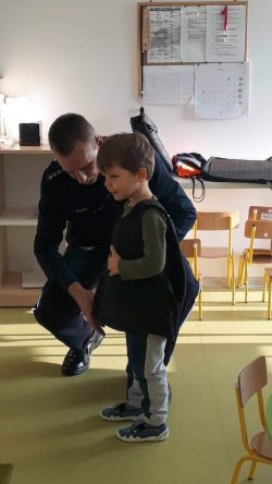 Przedszkolak ubiera policyjną kamizelkę